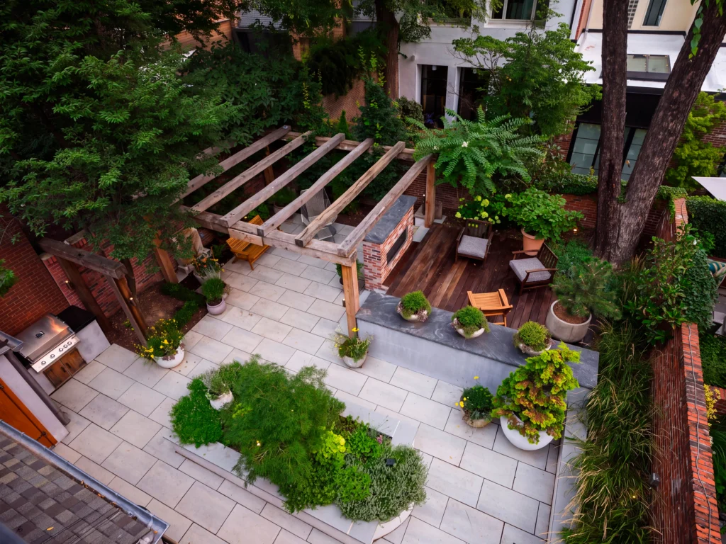 Custom courtyard outdoor living space with stone patio, timber pergola, outdoor kitchen and integrated garden planting designed by PLANT Design Group.