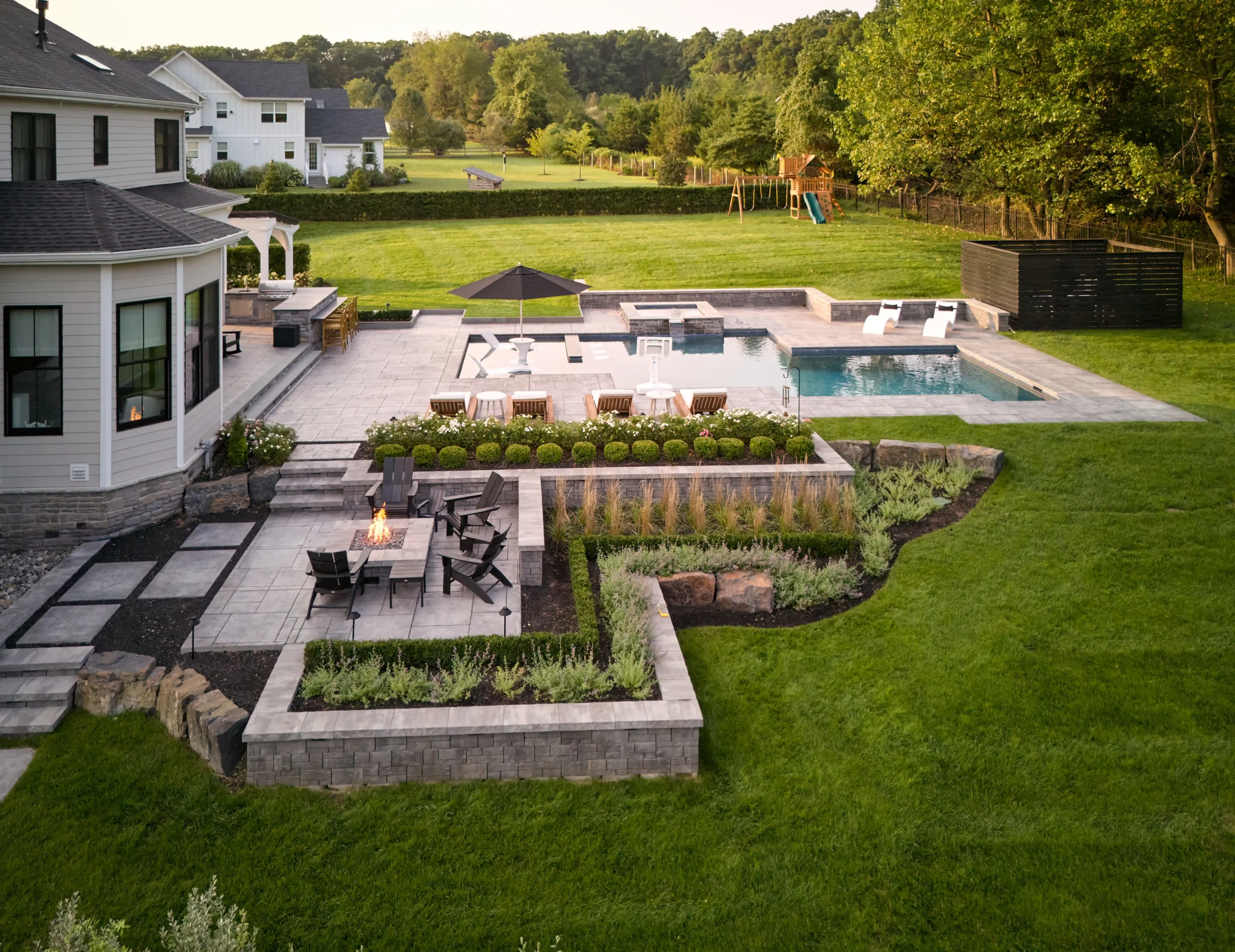 Complete landscape design-build project featuring a pool, outdoor kitchen, stone patios, fire pit and gardens in Bucks County, PA.