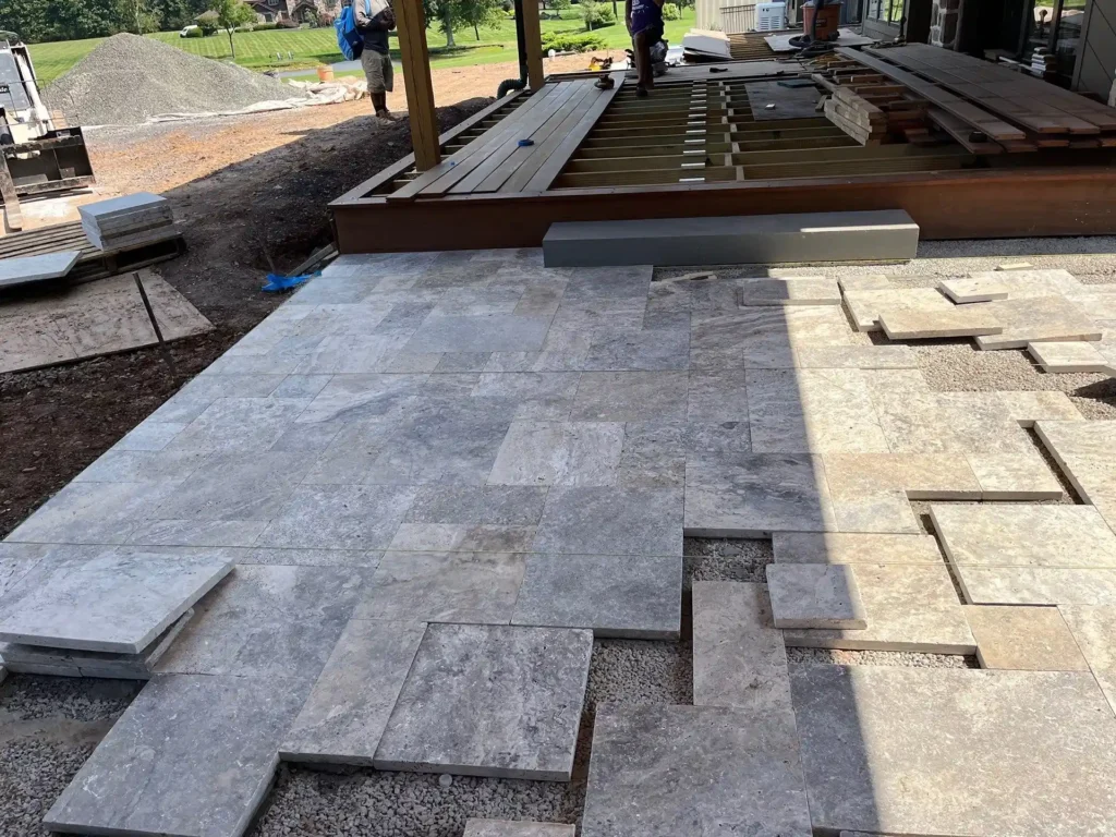 Natural stone patio installation beside custom deck construction during a landscape design-build project in Bucks County, PA.